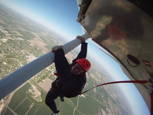 A static line student hanging from the wing before a first solo skydive at Skydive K-State
